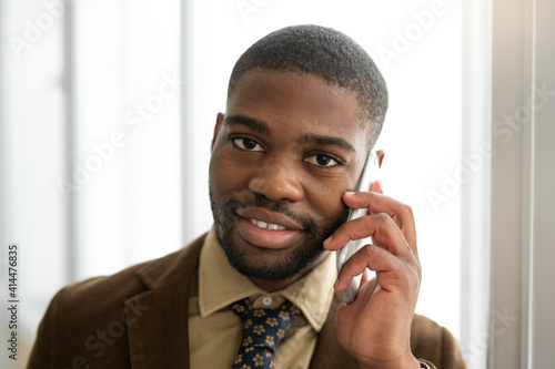 handsome young african man with mobile phone in suit at office 