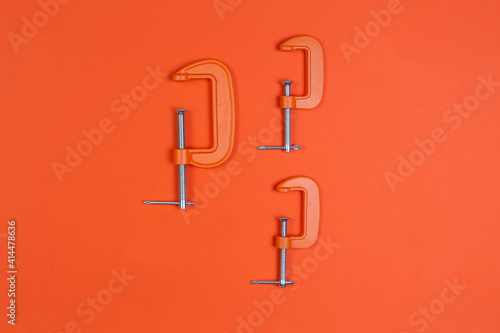 clamp, clamps on an orange background. compress, repair, construction.