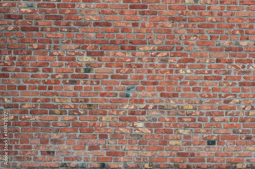 Old brick cracked wall, block with red fired clay, smooth rough surface, horizontal close-up photo.