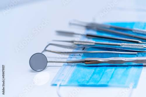Professional instruments for stomatology and maxillofacial surgery are beautifully laid out on the blue facial mask. Closeup.