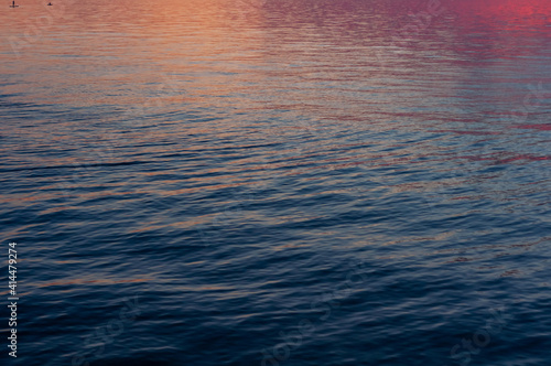 Blurred background, water surface, beautiful abstract background, reflected sky with sunrise, glow.