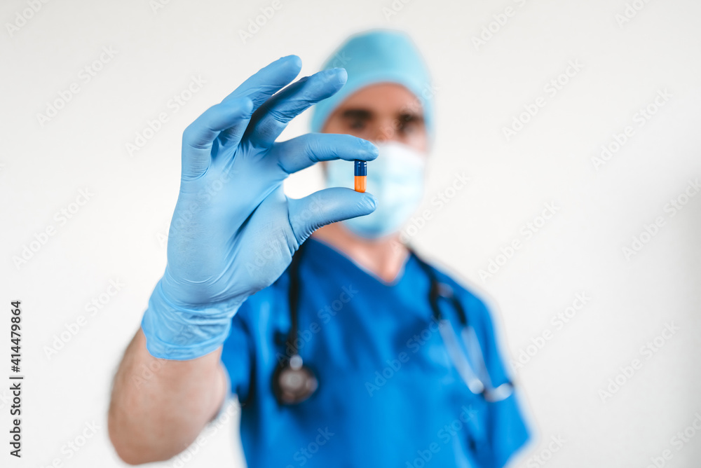 Doctor holding a pill with the fingers while using gloves Doctor holding a pill with the fingers while using gloves