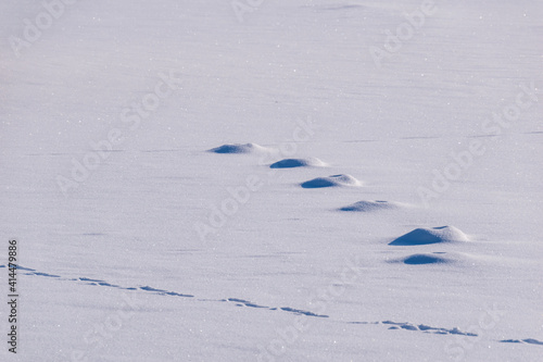 Feet and snow dunes in shimmering snow.