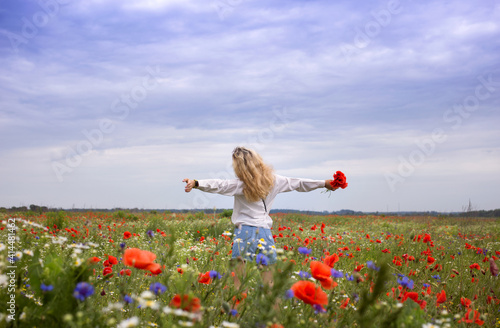 unrecognizable woman with her arms spread apart stands among red poppy flowers in meadow. Hello summer. digital detox, weekend in nature, search for inspiration, enjoy moment. Energy of the earth