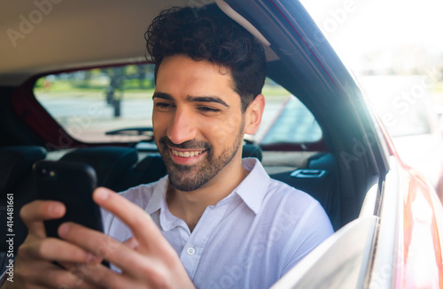 Businessman using mobile phone in car.