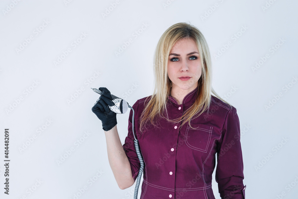 Slender young blonde girl master of manicure in black mask
A girl with long hair in a pink uniform, a manicure master in a protective black mask from the covid virus with tools for processing nails an
