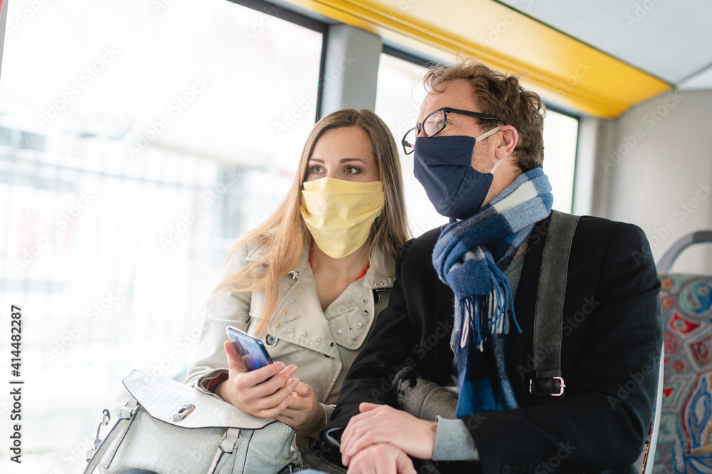Couple in public transport bus wearing masks - obrazy, fototapety, plakaty 