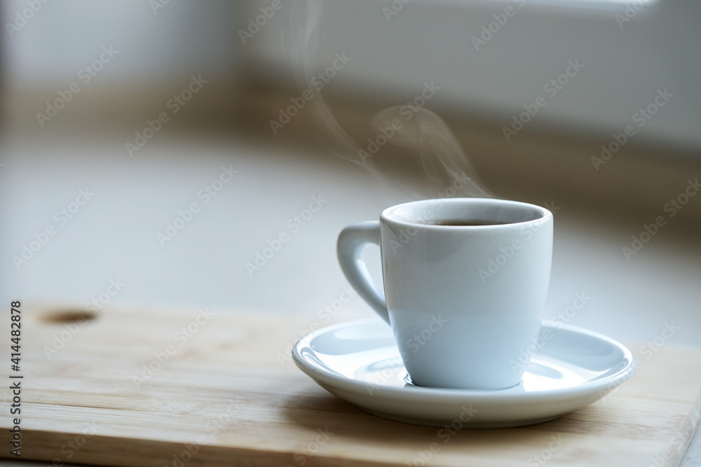 A white coffee cup with a transparent haze of steam over the hot drink. Selective focus. A white coffee cup with a transparent haze of steam over the hot drink. Selective focus.