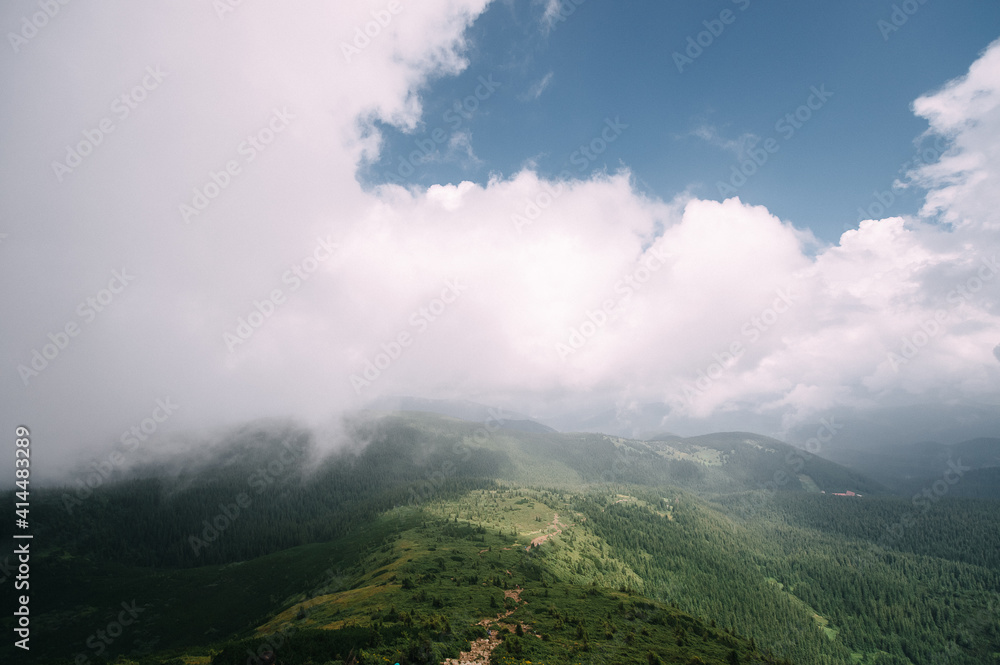 view from the top of mountain hoverla down, blue sky, clouds, thick fog, moss, conifers