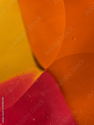floating oil drops shimmering in different colors and shapes next to air bubbles on a colored background 