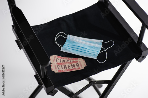 high angle view of safety masks and cinema tickets on filmmaker chair on white, cinema concept photo