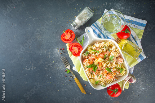 Spring diet healthy vegan pasta. Italian fusilli pasta with tomatoes, green vegetables, fresh herbs, cream cheese or feta, on white table background copy space