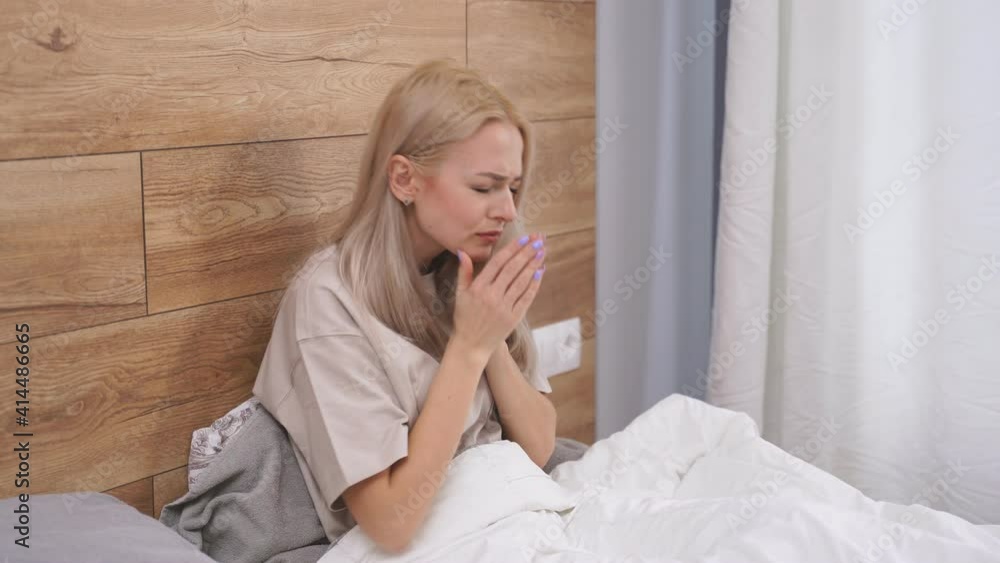 Woman ill with flu at home sitting on bed alone, having pain in throat. Sick caucasian female with seasonal infections flu allergy and runny nose. Coronavirus, covid-19 and medicine, healthcare Woman ill with flu at home sitting on bed alone, having pain in throat. Sick caucasian female with seasonal infections flu allergy and runny nose. Coronavirus, covid-19 and medicine, healthcare