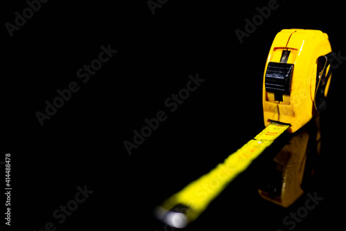 Old, used , scratched yellow tape measurer on shiny dark surface, focus on the number 10, space for text.