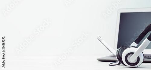 Laptop. Mockup screen and headphones on white desk grey background banner. Distant learning or working from home, online courses or shopping minimal concept. Helpdesk or call center headset