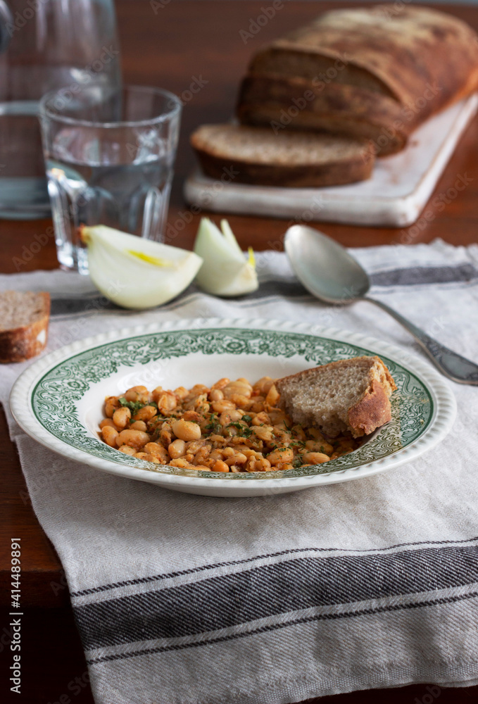 Bean stew, ciabatta and onions on a wooden table. Bean stew, ciabatta and onions on a wooden table.