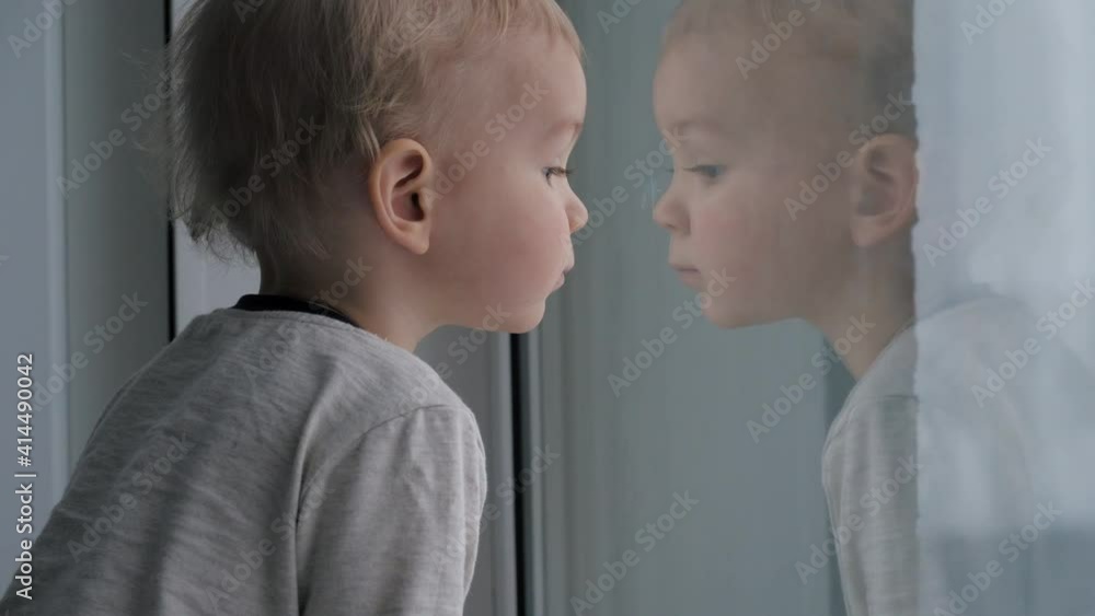 Inquisitive Kid Baby Looks With Interest Out The Window At The Street Inquisitive Kid Baby Looks With Interest Out The Window At The Street