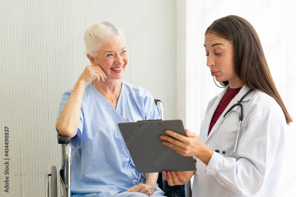 © ake - Caucasian old senior depressed upset woman patient on wheelchair talking to medical doctor with stethoscope  in hospital