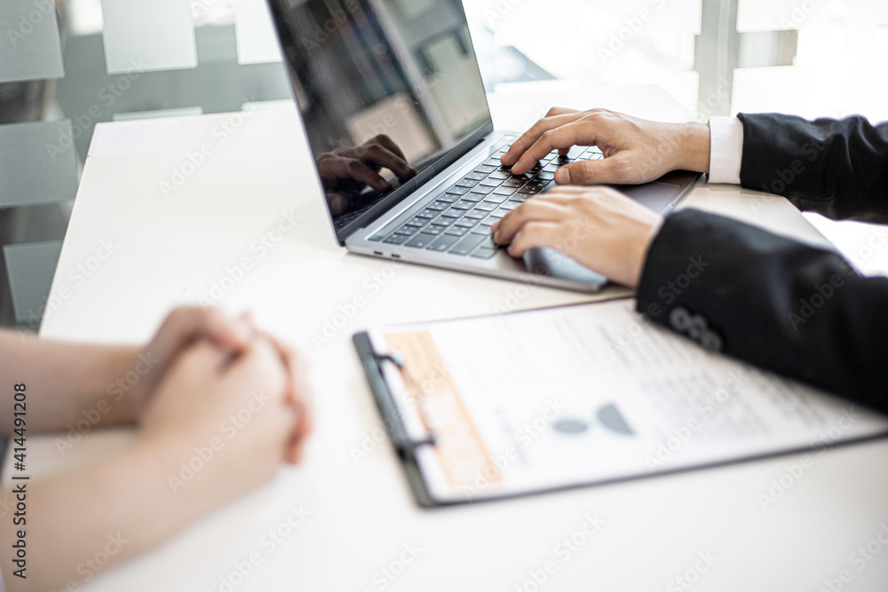 Manager typing on laptop keyboard while interviewing with female job applicants. Manager typing on laptop keyboard while interviewing with female job applicants.