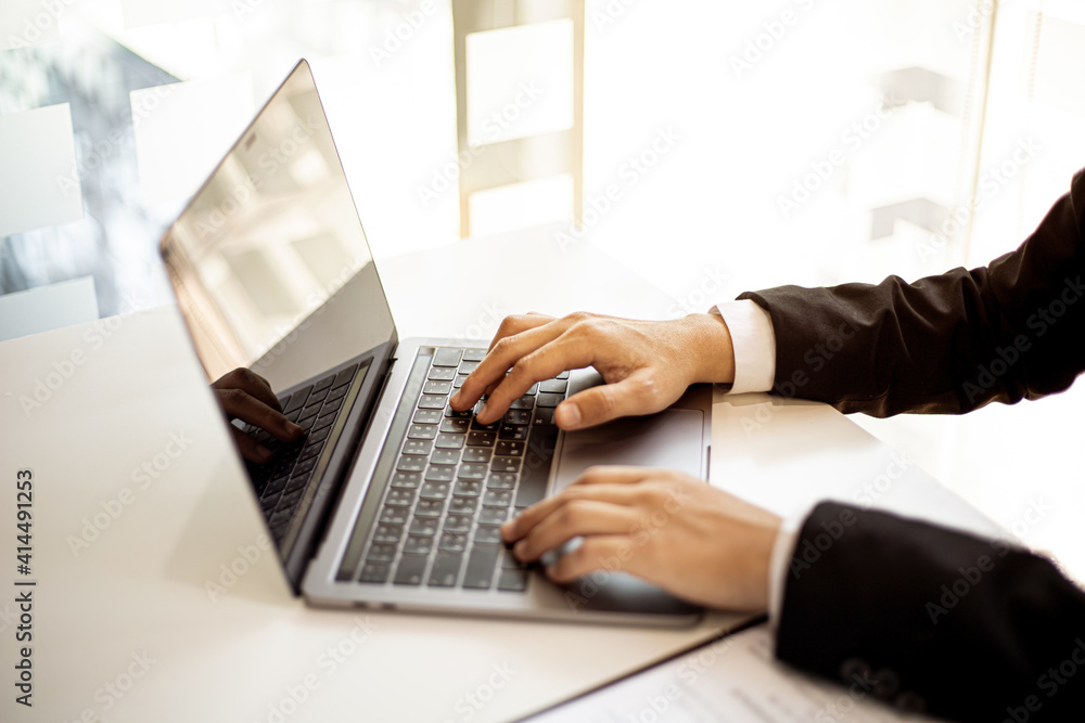 A businessman sitting on a laptop typing a keyboard in his office. A businessman sitting on a laptop typing a keyboard in his office.