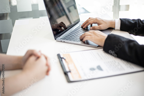 Manager typing on laptop keyboard while interviewing with female job applicants.