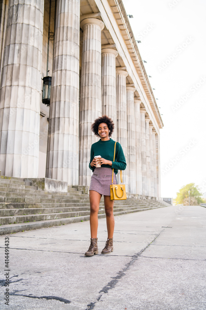 Afro businesswoman walking outdoors on the street.