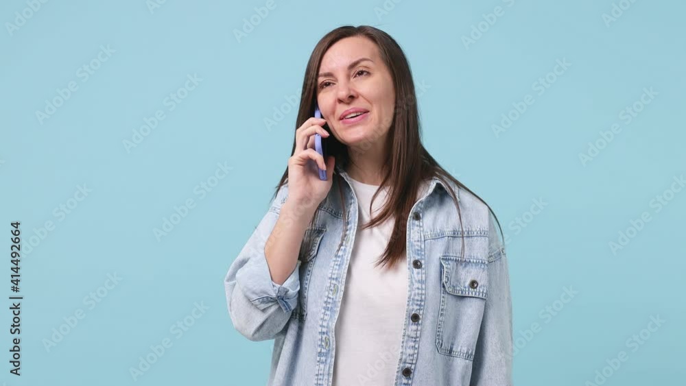Happy excited surprised joyful young woman in denim jacket white tshirt hold talk use mobile cell phone just found out great big win news doing winner gesture isolated on pastel blue background studio Happy excited surprised joyful young woman in denim jacket white tshirt hold talk use mobile cell phone just found out great big win news doing winner gesture isolated on pastel blue background studio