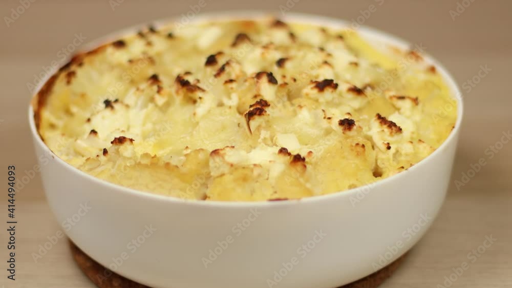 Homemade cauliflower, chicken and cheese casserole with spices in a dish on a wooden background. Female hands put dish with freshly baked pie Homemade cauliflower, chicken and cheese casserole with spices in a dish on a wooden background. Female hands put dish with freshly baked pie