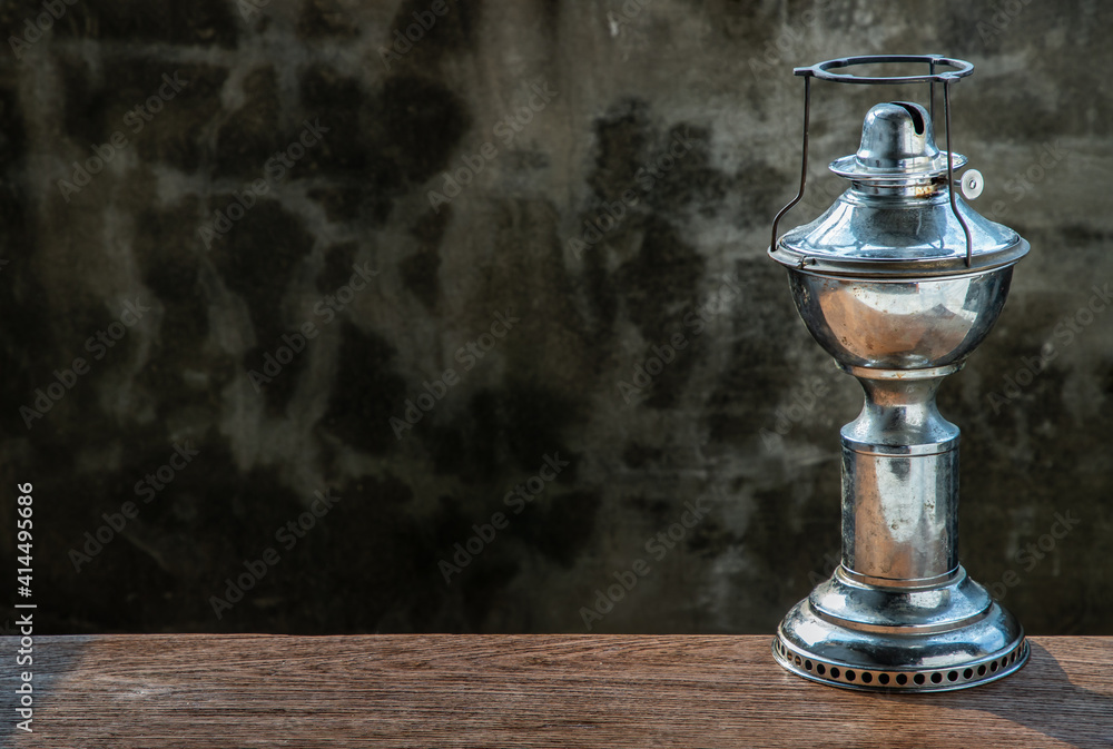 An ancient kerosene (oil) lamp on rustic old wooden background with old cement wall. Vintage, Retro, Copy space, Selective focus. An ancient kerosene (oil) lamp on rustic old wooden background with old cement wall. Vintage, Retro, Copy space, Selective focus.
