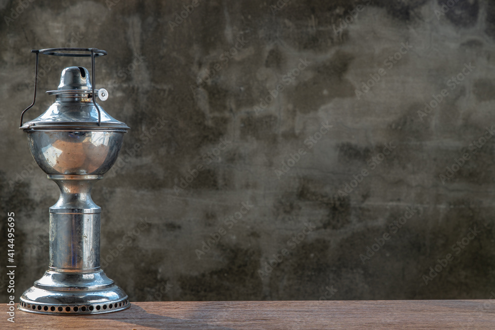 An ancient kerosene (oil) lamp on rustic old wooden background with old cement wall. Vintage, Retro, Copy space, Selective focus.