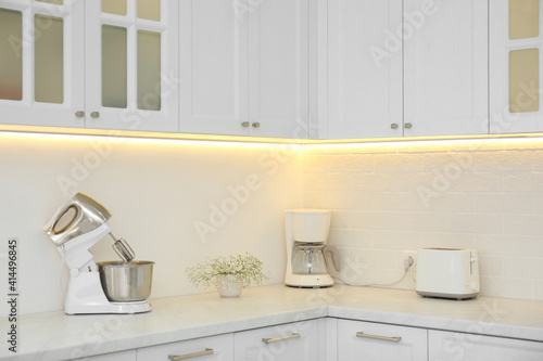 Modern toaster and household appliances on counter in kitchen