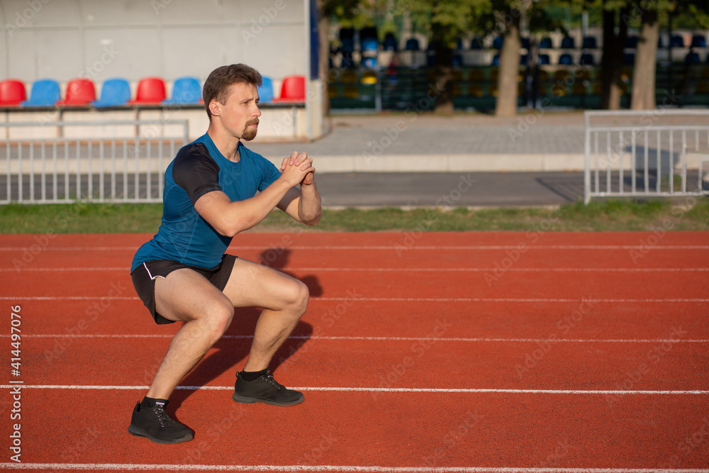 Fototapeta premium Strong bearded guy doing squats at the stadium