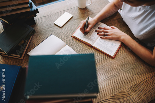 Woman writing notes in notebook in library