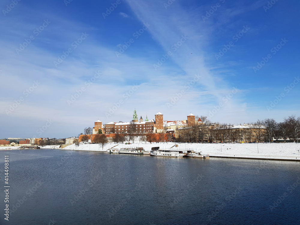 Panoramic view of The Wawel Royal Castle located on the left bank of the Vistula River in city Krakow, Poland. Sunny winter day, big blue sky, white clouds lines.