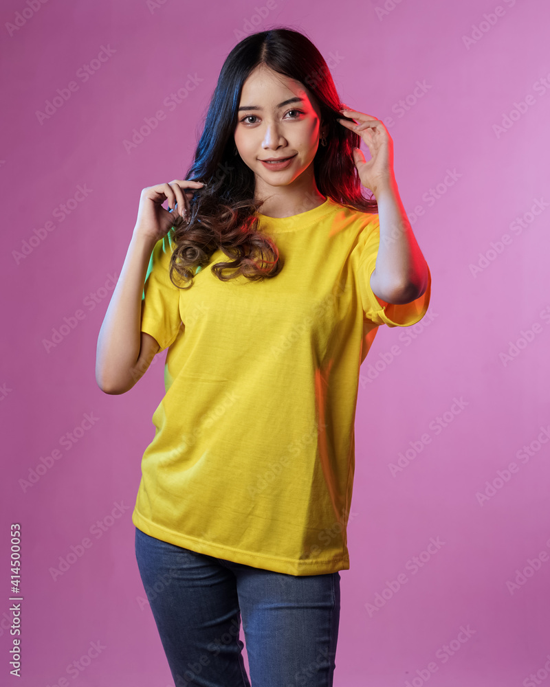 Young female model wearing blank T-shirt in studio background. Woman in cheerful pose with blue and red lighting. Modern shirt mockup. Young women are stylish like adult models. Pretty sheer makeup. Young female model wearing blank T-shirt in studio background. Woman in cheerful pose with blue and red lighting. Modern shirt mockup. Young women are stylish like adult models. Pretty sheer makeup.