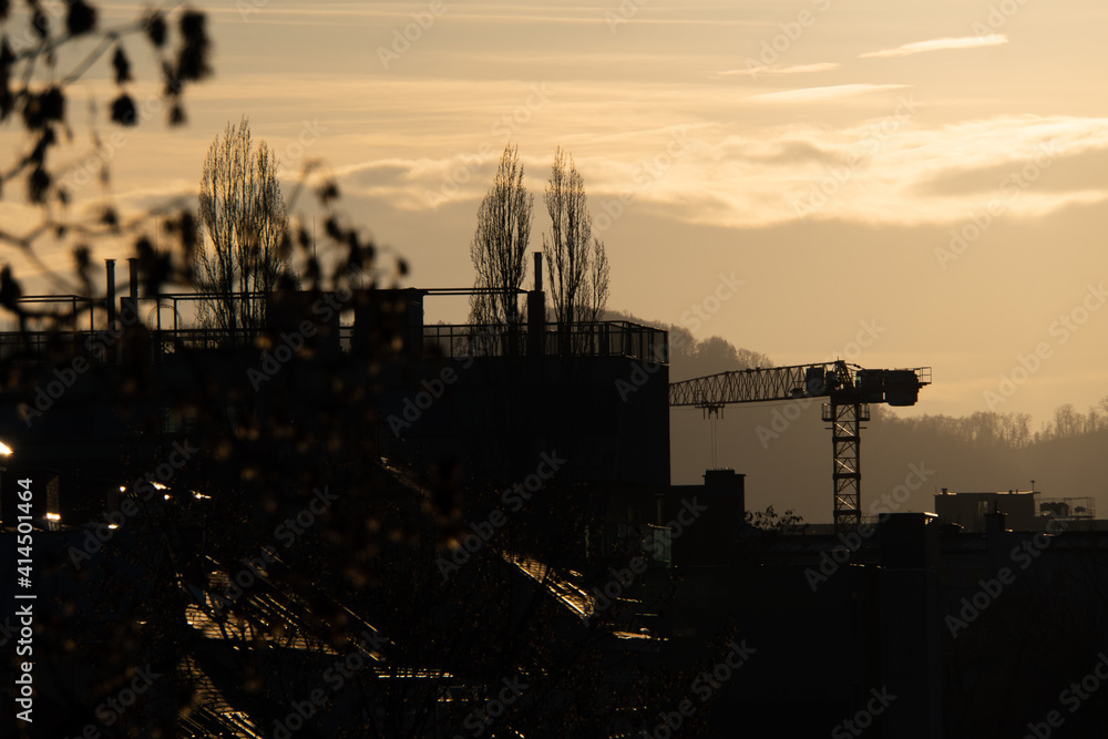 Skyline mit Kran und Bergen bei Sonnenuntergang