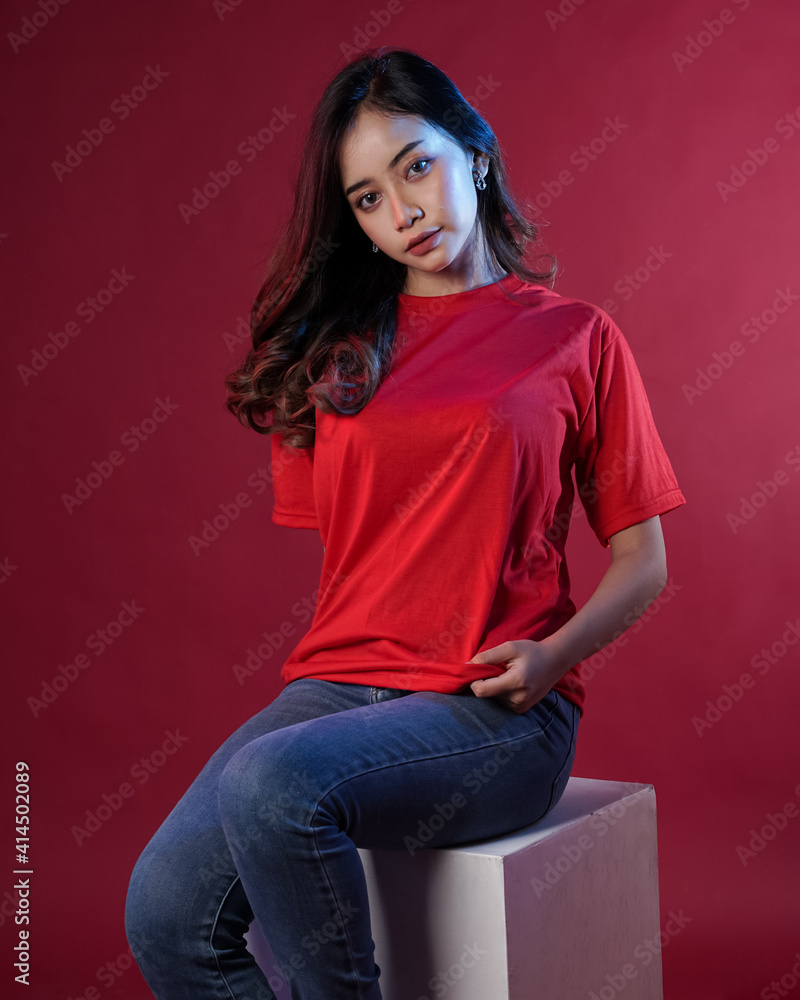 Young female model wearing blank T-shirt in studio background. Woman in cheerful pose with blue and red lighting. Modern shirt mockup. Young women are stylish like adult models. Pretty sheer makeup. Young female model wearing blank T-shirt in studio background. Woman in cheerful pose with blue and red lighting. Modern shirt mockup. Young women are stylish like adult models. Pretty sheer makeup.