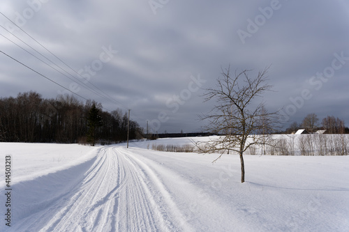  road in the middle of the field that is covered with snow © Rolands