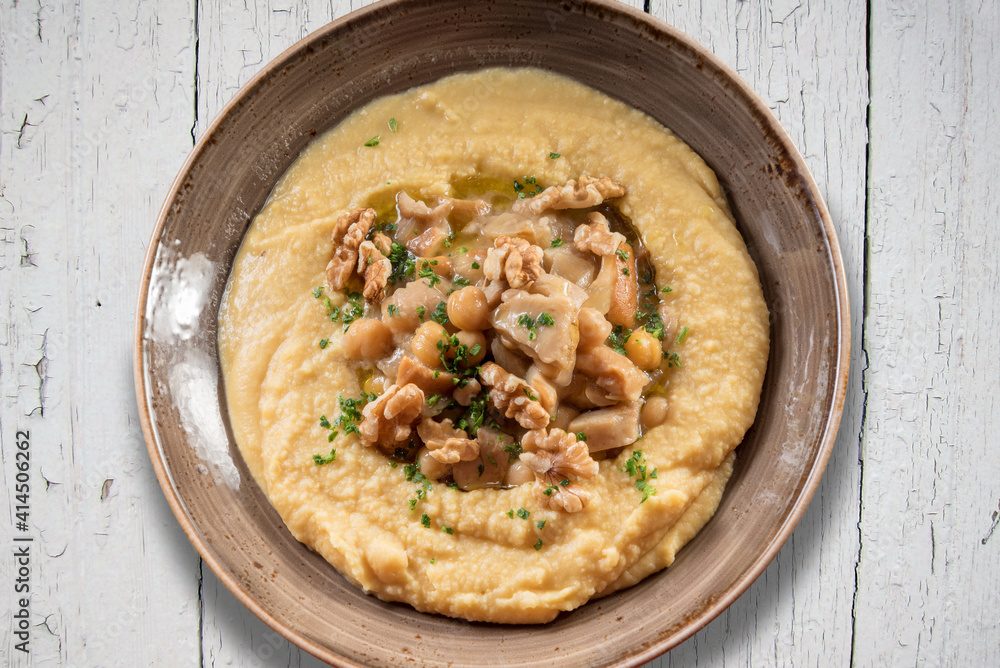 Hummus with parsley, olive oil and walnuts. Israeli chickpea cream in earthenware bowl on rustic table, top view, flat lay Hummus with parsley, olive oil and walnuts. Israeli chickpea cream in earthenware bowl on rustic table, top view, flat lay