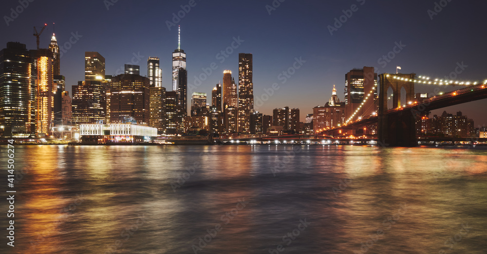 Manhattan skyline and Brooklyn Bridge reflected in water at dusk, New York City, USA.