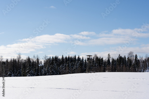 white fluffy snow and on it stands a large hunting tower built of wood © Rolands