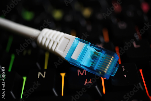 Makro closeup of isolated blue white network connector cable on illuminated computer keyboard photo