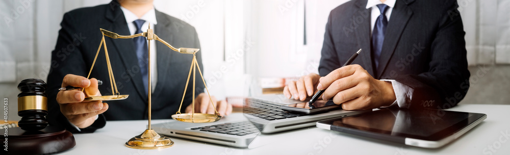 Justice and law concept.Male judge in a courtroom with the gavel, working with, computer and docking keyboard, eyeglasses, on table in morning light Justice and law concept.Male judge in a courtroom with the gavel, working with, computer and docking keyboard, eyeglasses, on table in morning light