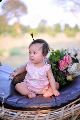 Portrait cute baby girl of 8 months old enjoying, Asia child happy siting on black sofa.