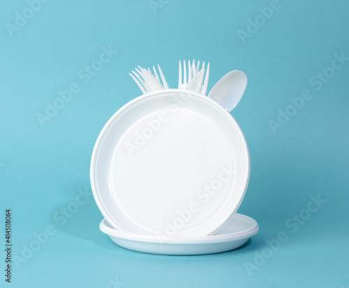 Slika na platnu disposable white plastic tableware plates, cups, forks and knives on a blue back