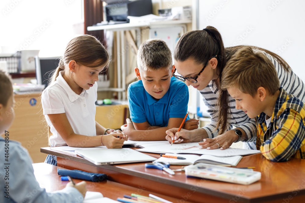Female teacher helps school kids to finish they lesson.They sitting all together at one desk.
Female teacher helps school kids to finish they lesson.They sitting all together at one desk.