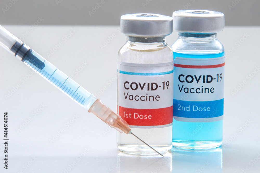 1st dosis and a 2nd dosis of covid-19 vaccine on a vial bottle and injection Syringe on a white table 1st dosis and a 2nd dosis of covid-19 vaccine on a vial bottle and injection Syringe on a white table