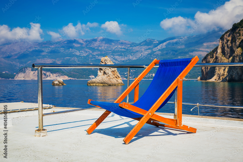 View over the board of a boat on sea and grey rock islands with sun loungers View over the board of a boat on sea and grey rock islands with sun loungers