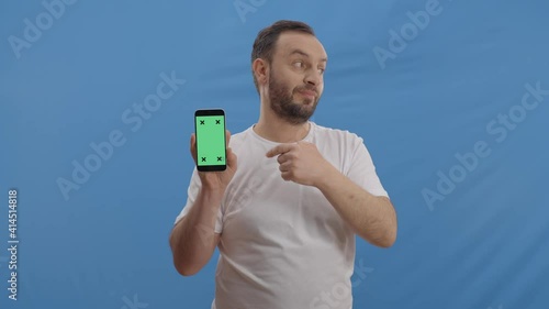 Green shielded holding cell phone tracking spot and the young man against a blue background. After showing the phone, it shows the ad space behind it. Slow motion video. photo