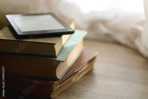 Foto Stack of vintage books and e-book reader on top. Selective focus.